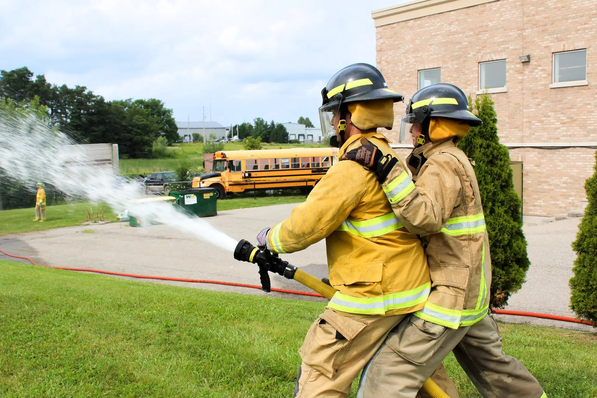 Firefighter recruits working together to operate a hose during outdoor training