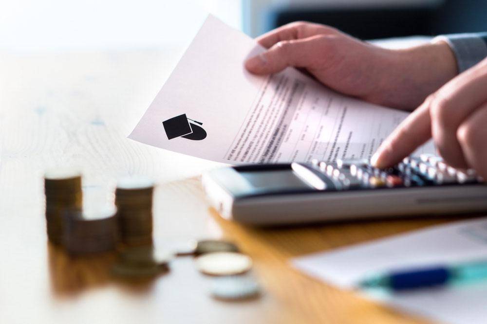 Person calculating tuition and accommodation costs with a calculator