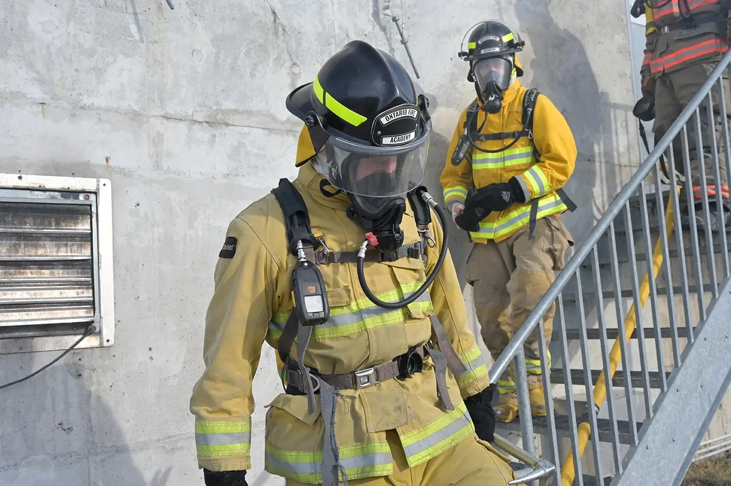 Firefighter students wearing full turnout gear and SCBA masks on a training structure