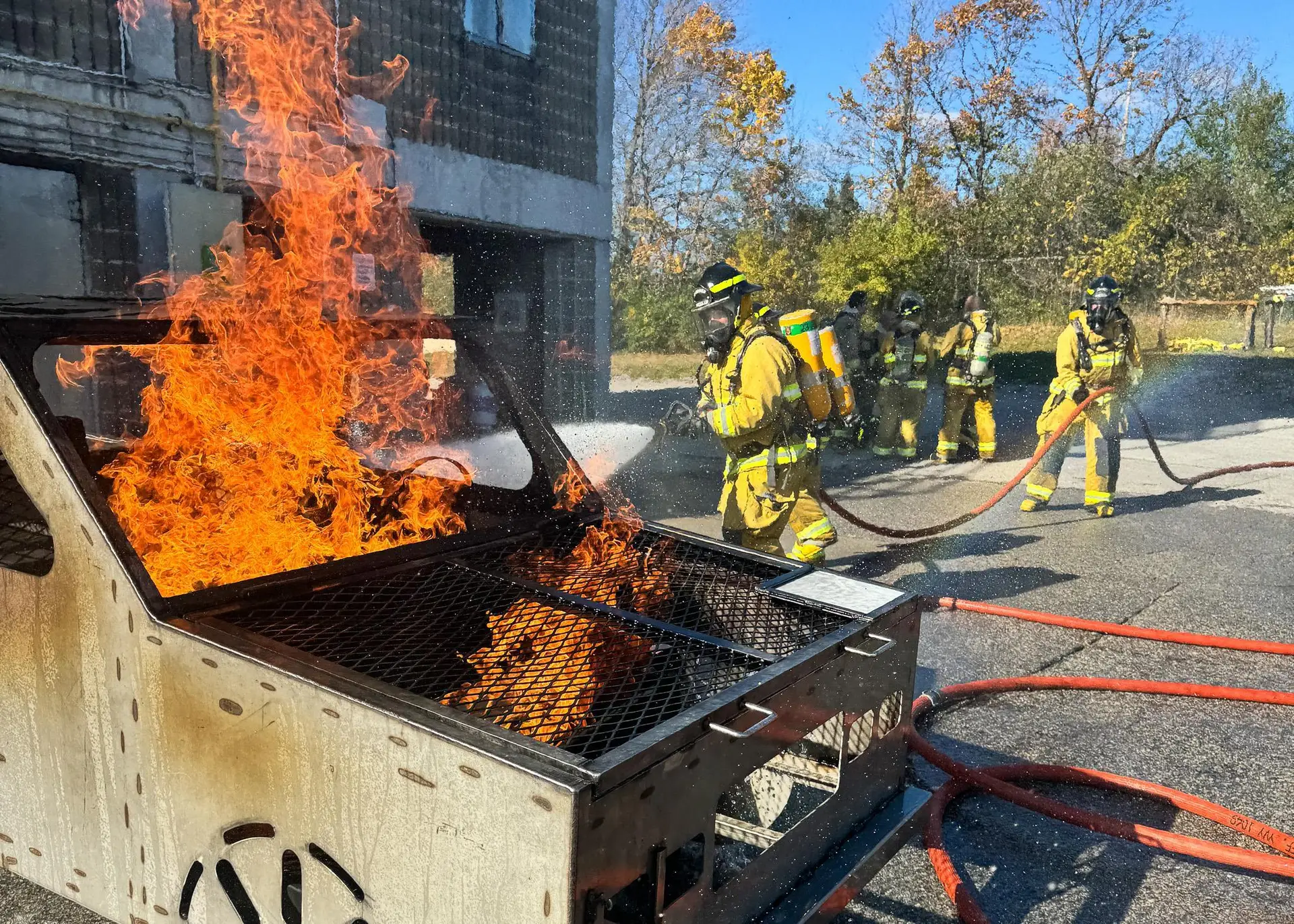 Firefighters training at a live burn prop with flames