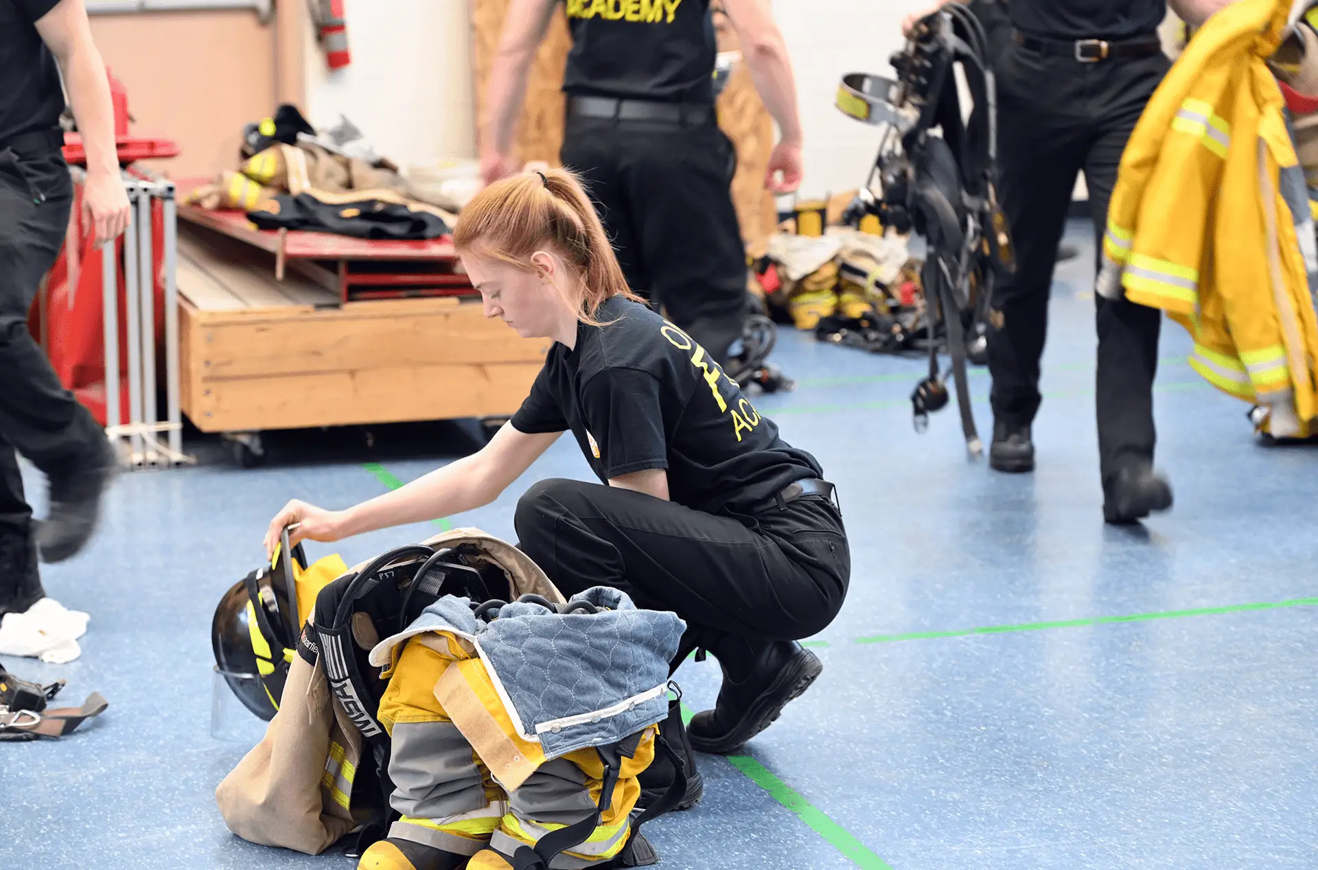 Recruit organizing firefighting turnout gear on the floor