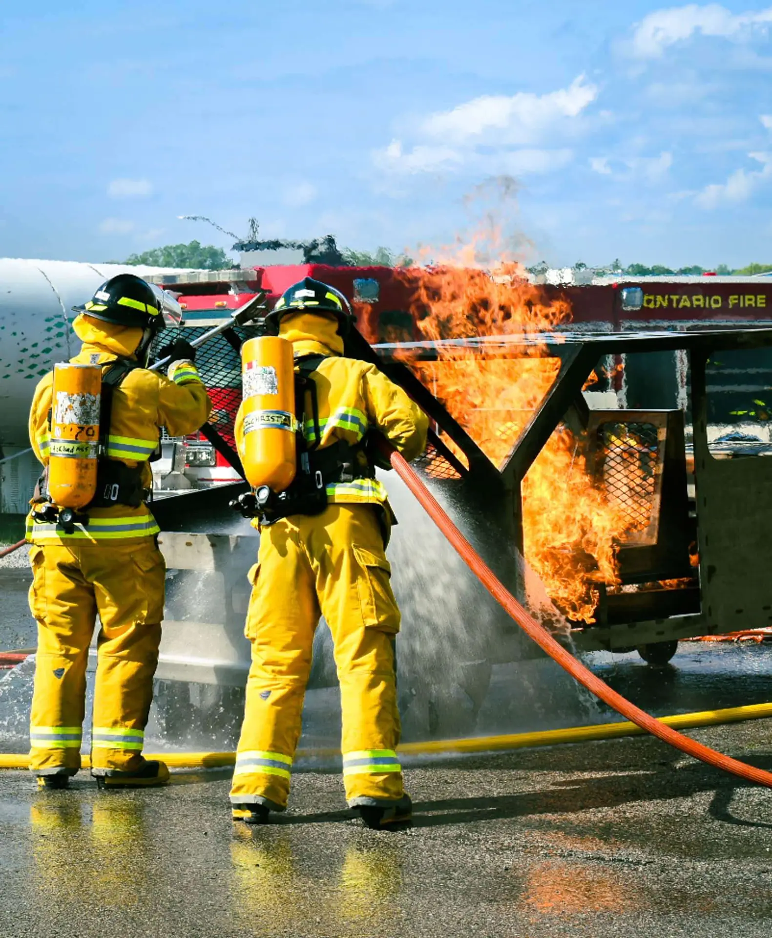 Firefighters using a hose to fight a live fire during training