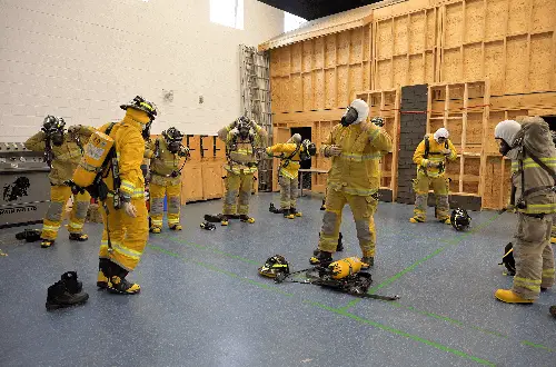 Recruits training indoors with firefighting gear at Ontario Fire Academy