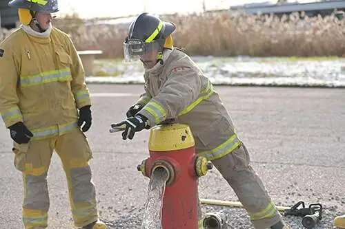 Firefighter recruit operating a fire hydrant during training