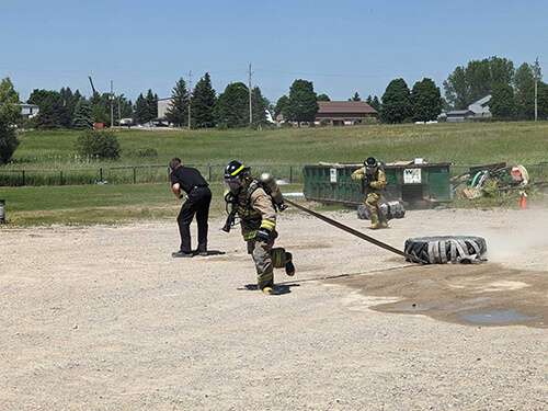 Firefighter recruit performing a tire-drag exercise during outdoor boot-camp training