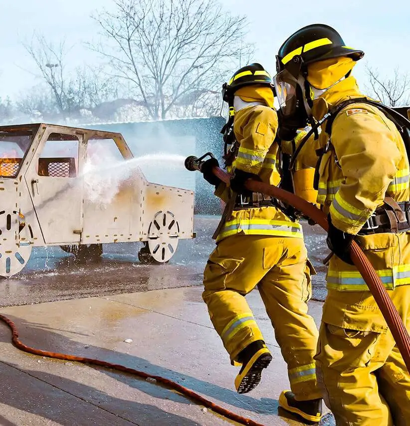 Firefighter students extinguishing a training fire with a hose