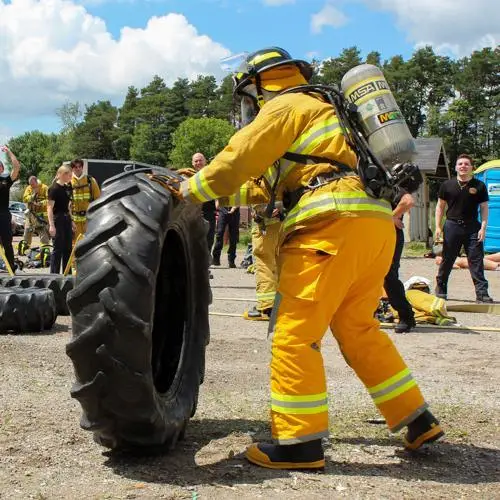 Firefighter recruit flipping a large tire during outdoor boot-camp training